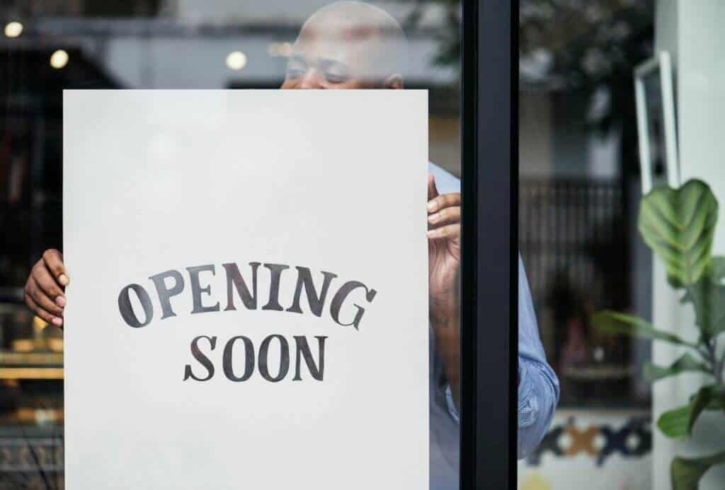 Man putting on store opening soon sign